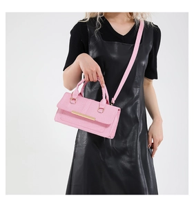 Pink textured leather shoulder bag with gold metal trim and thick handle detail
