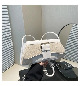 Close-up of beige crocodile texture shoulder bag with large metal buckle detail