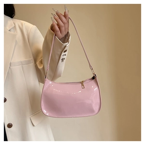 Detail of glossy pink patent leather underarm bag with gold zipper and minimalist design