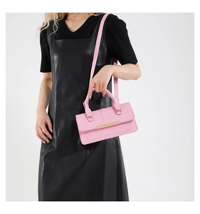 Detailed view of a pink leather crossbody bag featuring a sleek gold metal bar buckle