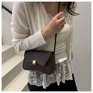 Detail of dark brown faux crocodile leather bag with asymmetric flap and gold square lock