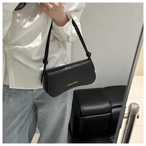 Detail of black woven texture shoulder bag with gold logo and stylish knotted strap