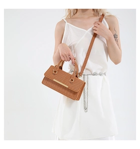 Detailed shot of woven texture caramel brown crossbody bag with gold buckle hardware