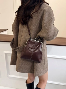 Detailed close-up of vintage brown leather kiss-lock bag with white contrast stitching