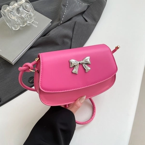 Detail of hot pink shoulder bag featuring a silver metal bow clasp and matte leather texture