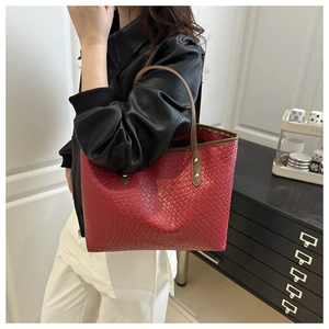 Detail of dark red woven tote bag with brown handles on a model in minimalist interior