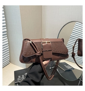 Close-up of dark brown crocodile texture pattern and gold buckle detail on bag