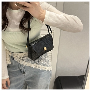 Detail of black faux snakeskin leather texture and gold metal clasp on a shoulder bag
