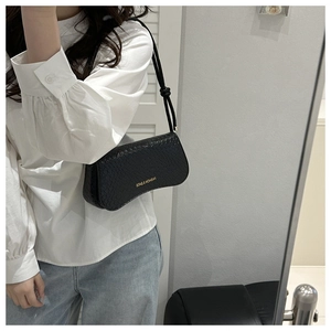 Close-up of black animal texture leather shoulder bag with gold brand lettering detail