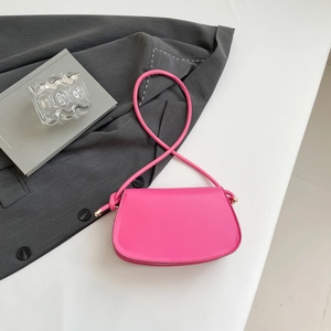 Close-up of hot pink crescent leather bag featuring stylish knot detail on long shoulder strap
