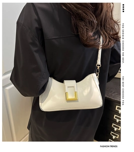 Détail d'un sac sous les aisselles crème avec boucle en métal doré et bandoulière en cuir