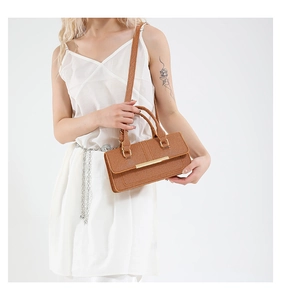 Detail of caramel woven texture handbag with gold metal bar and thin shoulder strap