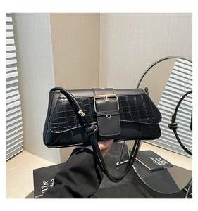 Detail of crocodile embossed leather texture and large metal buckle on black shoulder bag