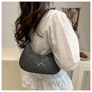 Model wearing black shimmering hobo bag with a silver metal bow buckle on a white blouse