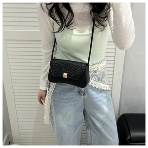 Close-up of black woven texture shoulder bag with elegant golden square metal clasp