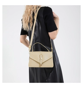 Golden woven texture crossbody bag with metal buckle shown on black leather dress