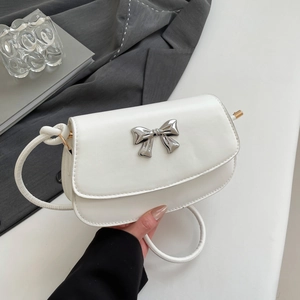 Close-up of white PU leather shoulder bag featuring a silver metal bow buckle detail