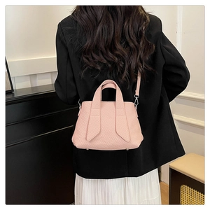 Pink striped tote bag styled as a shoulder bag on a model wearing a black blazer
