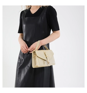Detail of champagne gold textured handbag with metallic clasp and handle on model