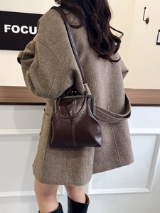 Detail of dark brown retro kiss-lock bag showing silver metal frame and white stitching