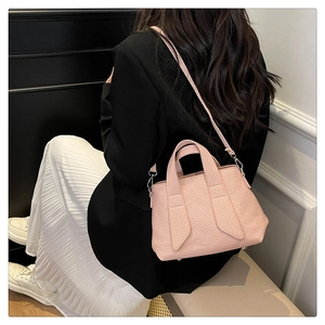 Close-up of pink textured crossbody tote bag worn by model showing its actual size and scale