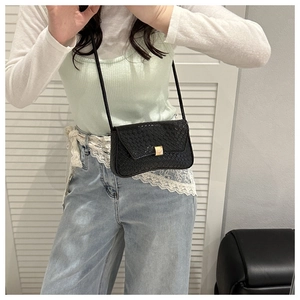 Close-up of black woven shoulder bag with gold square buckle on casual model look