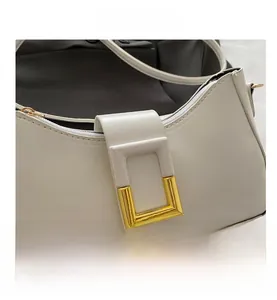 Détail d'un sac à main en cuir blanc crème avec boucle dorée polie et fermeture éclair