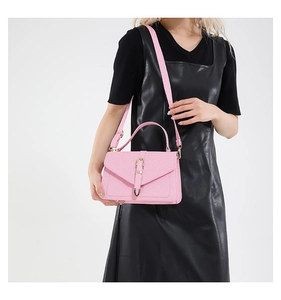 Close-up of pink crossbody bag with woven texture and gold buckle on a model