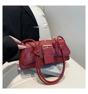 Close-up of red crocodile embossed leather flap with decorative silver buckle on handbag