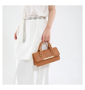 Close-up of brown textured leather shoulder bag with golden metallic bar and square ring