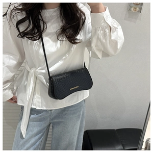 Mirror selfie showing a black woven-texture crossbody bag with gold fashion lettering