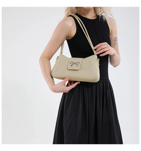 Détail du sac baguette beige avec nœud métallique et fine bandoulière élégante