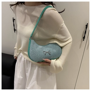 Detail of light blue glitter hobo bag with green strap and silver bow on model