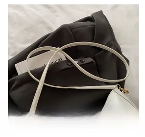 Détail d'un sac porté épaule blanc avec boucle dorée et bandoulière fine et ajustable