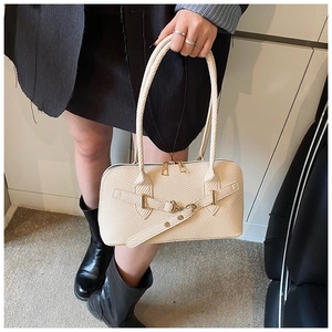 Detail of off-white woven pillow bag featuring a gold metal twist lock and strap
