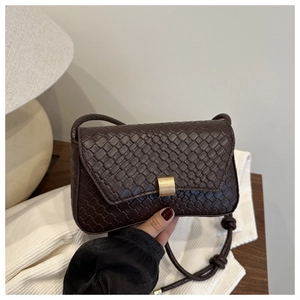 Detail of dark brown woven texture shoulder bag with gold metal buckle and cord strap