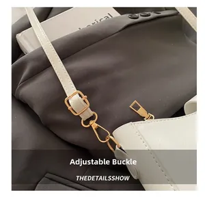 Détail de la boucle dorée ajustable et du fermoir mousqueton sur un sac en similicuir blanc
