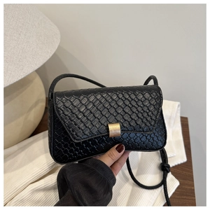 Detail of black woven shoulder bag featuring a golden metal buckle and sleek strap