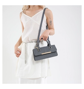 Detail of dark gray textured crossbody bag featuring elegant gold metal clasp and double handles