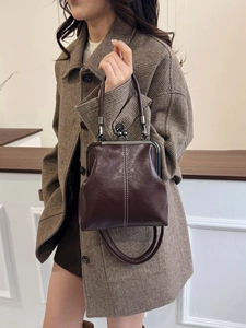 Detail of dark brown vintage doctor bag with contrast stitching and metal kiss-lock clasp