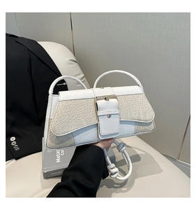 Close-up of white croc-embossed texture and golden buckle detail on shoulder bag