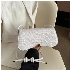 Close-up of white woven texture handbag with gold fashion lettering and metal strap tips