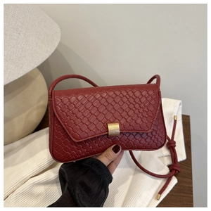 Detail of deep red woven texture on small shoulder bag with a gold rectangular buckle