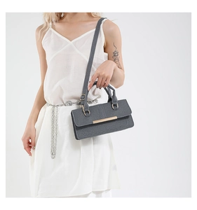 Detail of grey textured fabric crossbody bag with gold metal trim and long strap