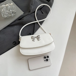 Top view of white minimalist handbag with silver bow detail next to a smartphone