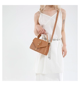 Detail of a brown woven texture handbag with golden hardware clasp and detachable strap