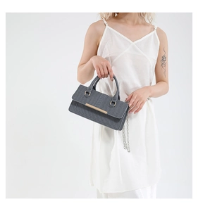 Gray denim crossbody bag with gold chain strap shown on model in minimalist style