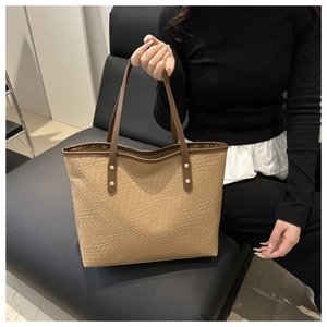 Detail of khaki woven texture tote bag with brown leather straps and gold rivets