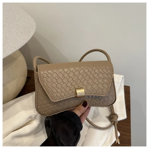 Detailed close-up of woven texture underarm bag with gold metal buckle and strap knot