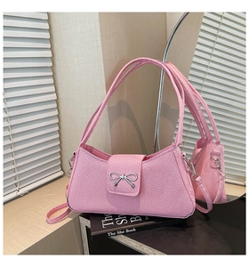 Vue détaillée du sac baguette en tissu rose avec un nœud métallique argenté et texturé